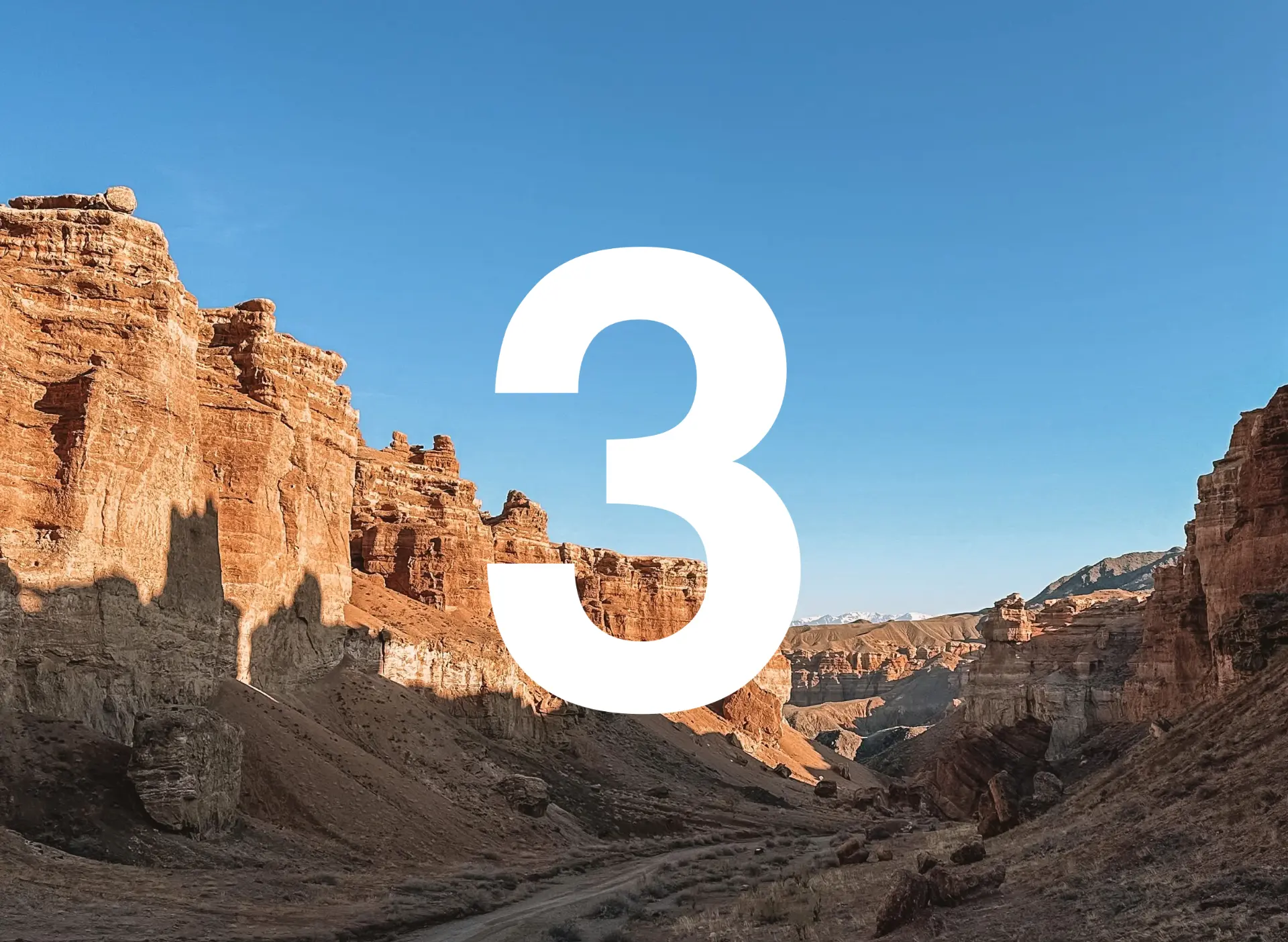 Red rock walls of Charyn Canyon under a clear blue sky, with the Day 3 numeral above